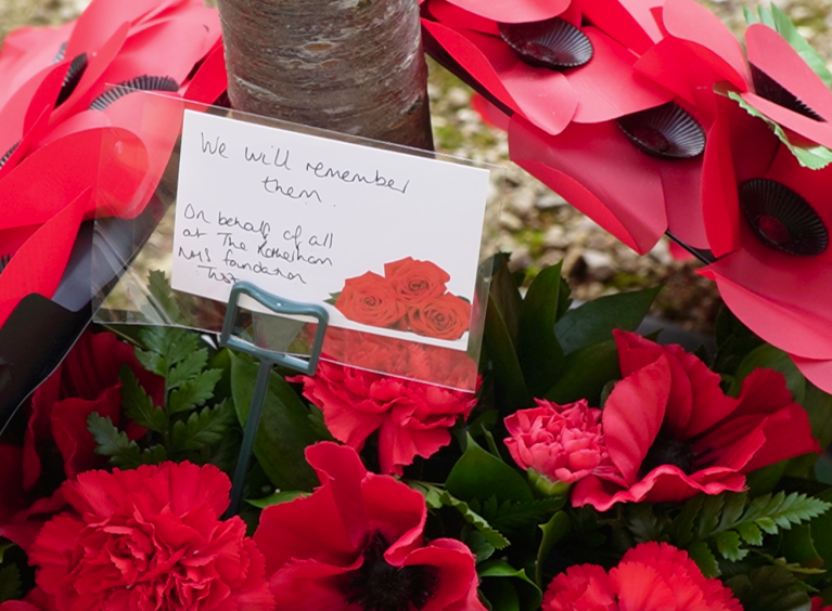 Poppy wreath with a card that says "We will remember them. On behalf of all at The Rotherham NHS Foundation Trust"