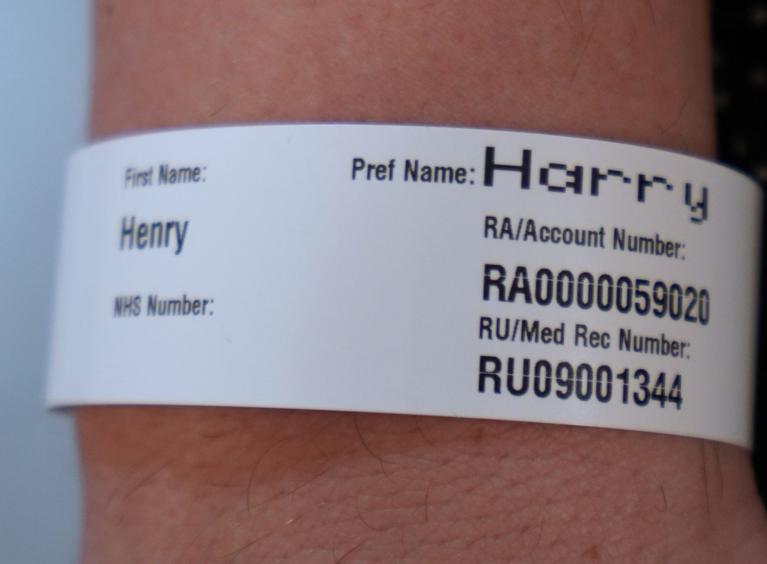 Hospital wristband on a person's arm showing their first name as Henry and preferred name as Harry