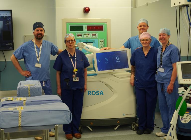 The image shows the surgery team with the Robotic Orthopaedic Surgical Assistant (ROSA).