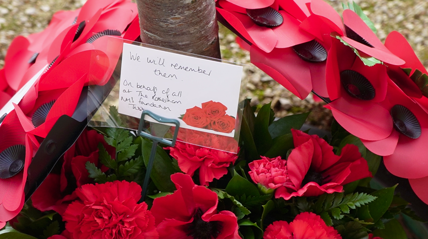 Poppy wreath with a card that says "We will remember them. On behalf of all at The Rotherham NHS Foundation Trust"