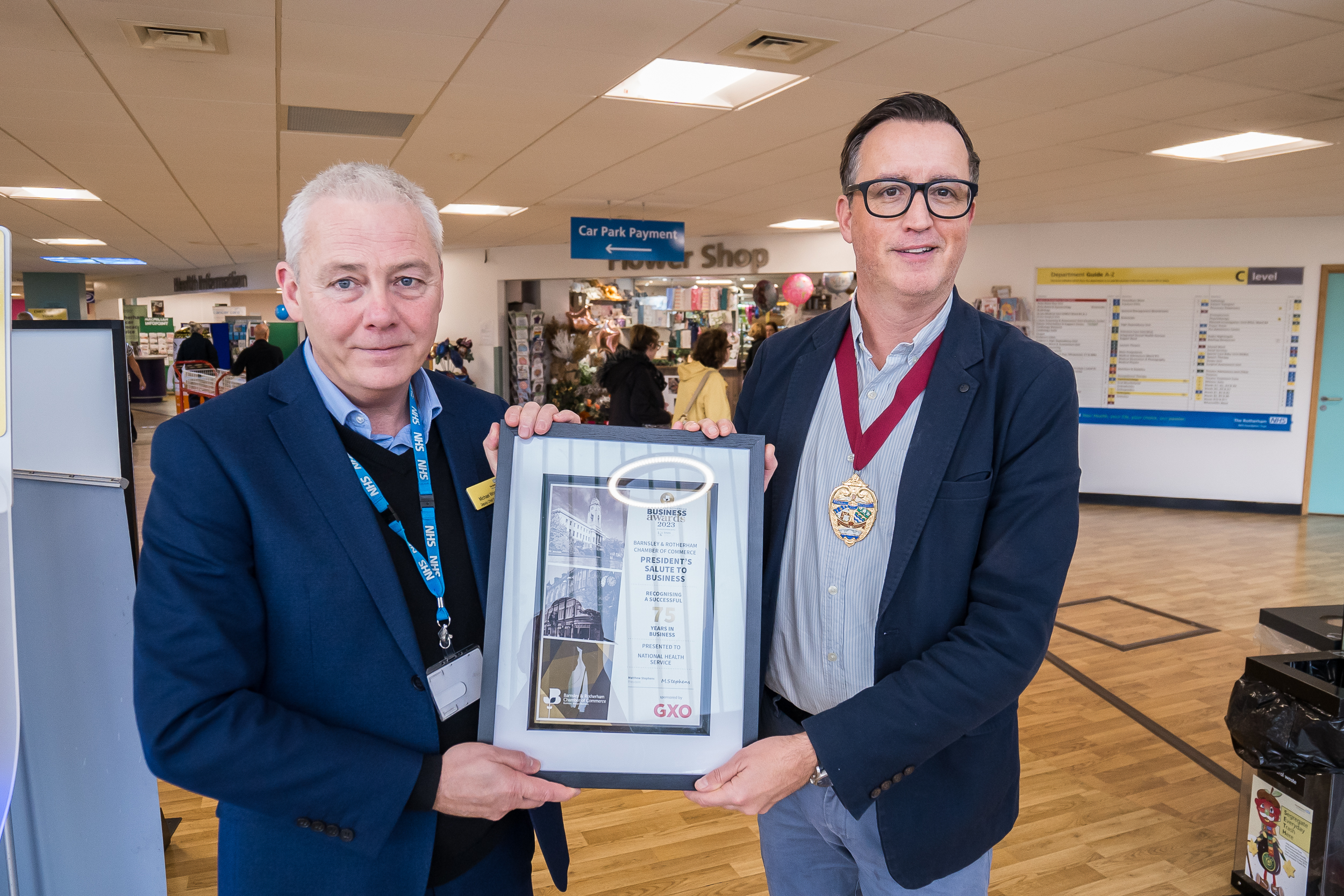 Michael Wright and Matthew Stephens in the main entrance of Rotherham Hospital, holding the 'President's salute to business' certificate.
