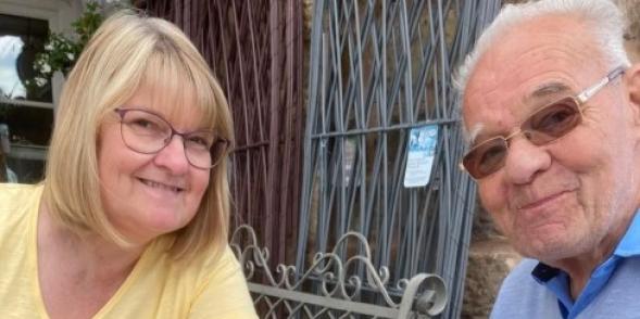 Sally Baker sits with her Dad having lunch. Both are smiling. 
