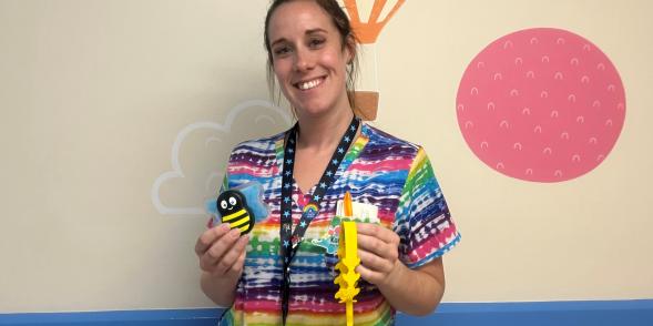 A nurse posing with a busy bee pain relief bee.