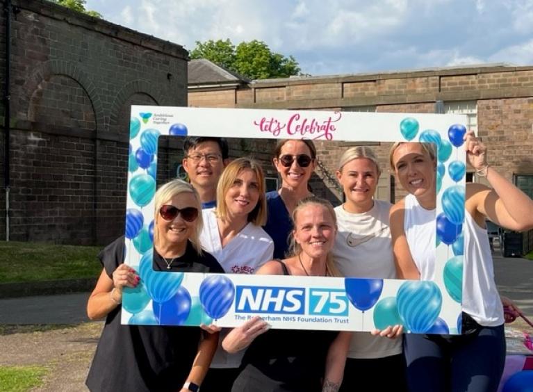Colleagues from UECC posing with an NHS75 photoframe