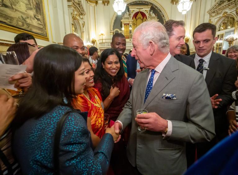 Swapna shaking hands with the King surrounded by other excited visitors to the Palace