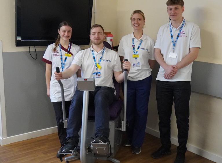 Four Trust colleagues wearing white t-shirts. One of them is on a cross cycle machine.