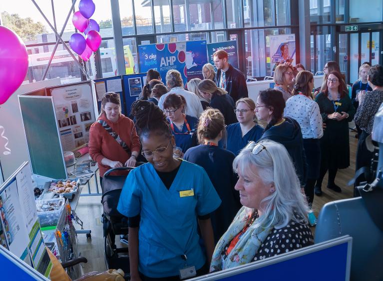 A group of people looking at information stands for AHP Day 2024