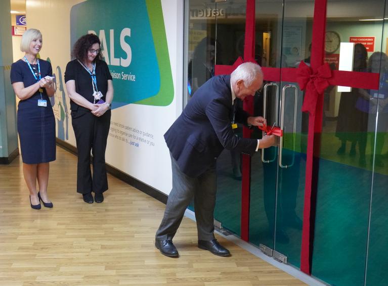 Dr Mike Richmond is cutting a red ribbon on the door of the PALS office