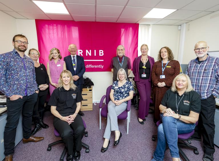 A group of people in front of a pink RNIB banner 
