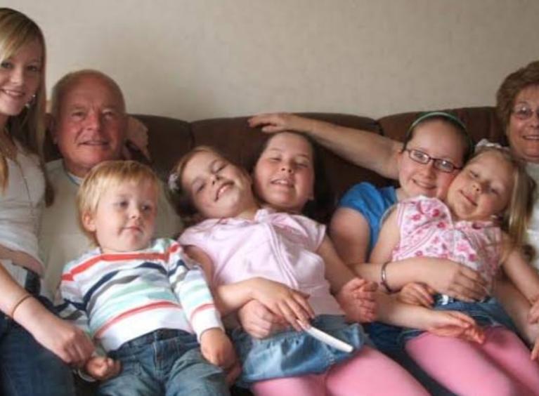 Sadie posing on a family photo with her siblings, cousins and Grandparents
