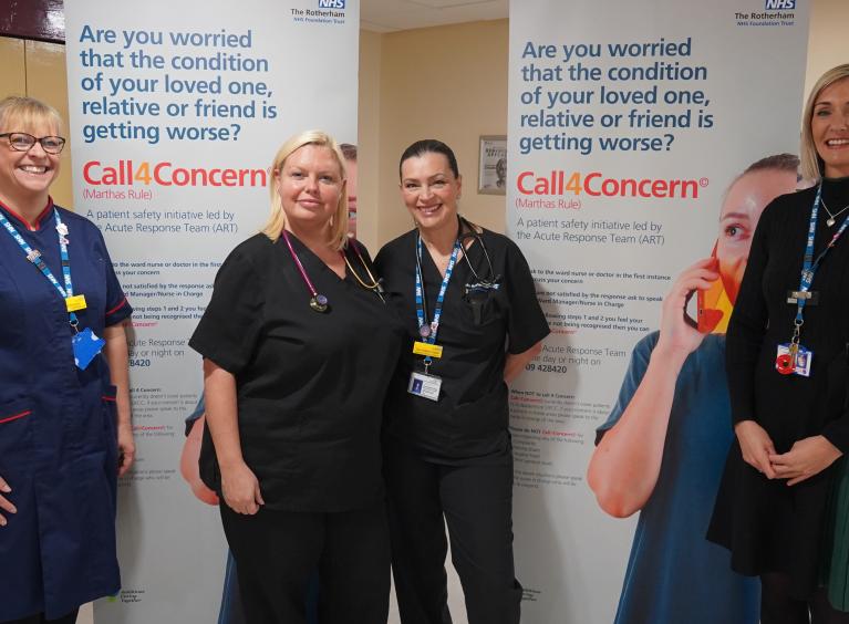 Four female clinical colleagues are stood in front of two pull-up banners promoting Call 4 Concern