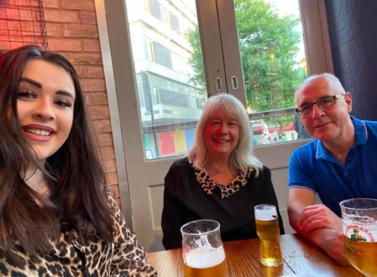 Beth sits happily in a restaurant with her mum and dad