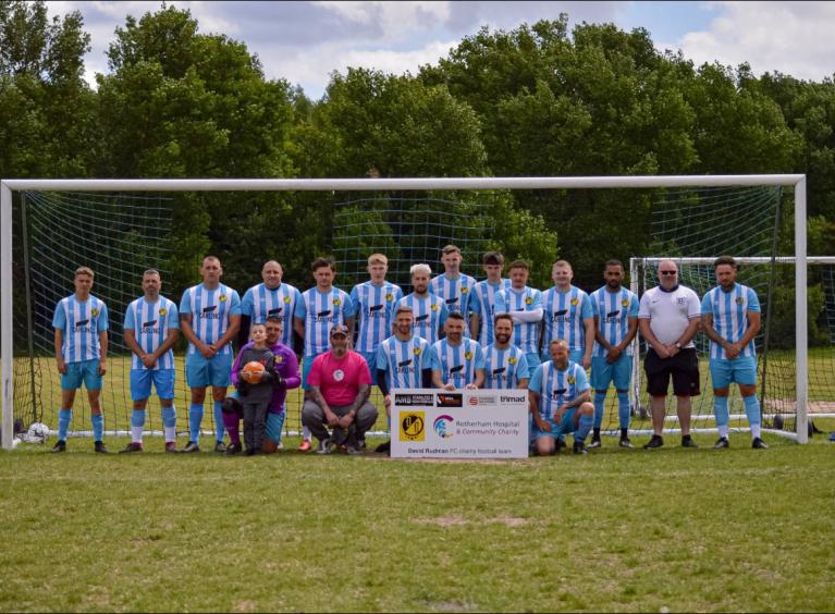 A football team, wearing light blue and white striped kit, stood in a goal