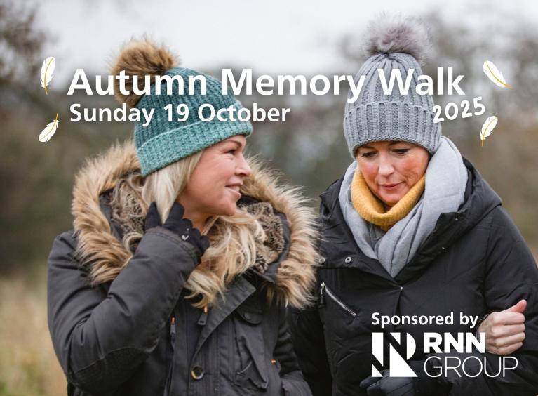 Two ladies walking together wearing winter coats and hats with the words 'Autumn Memory Walk 2025, Sunday 19 October. '