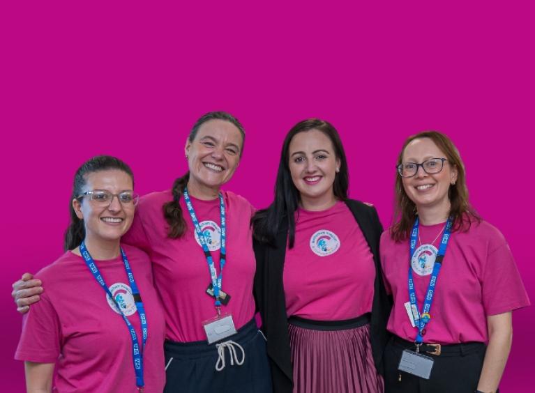 Four members of the charity team wearing branded t-shirts, smiling.