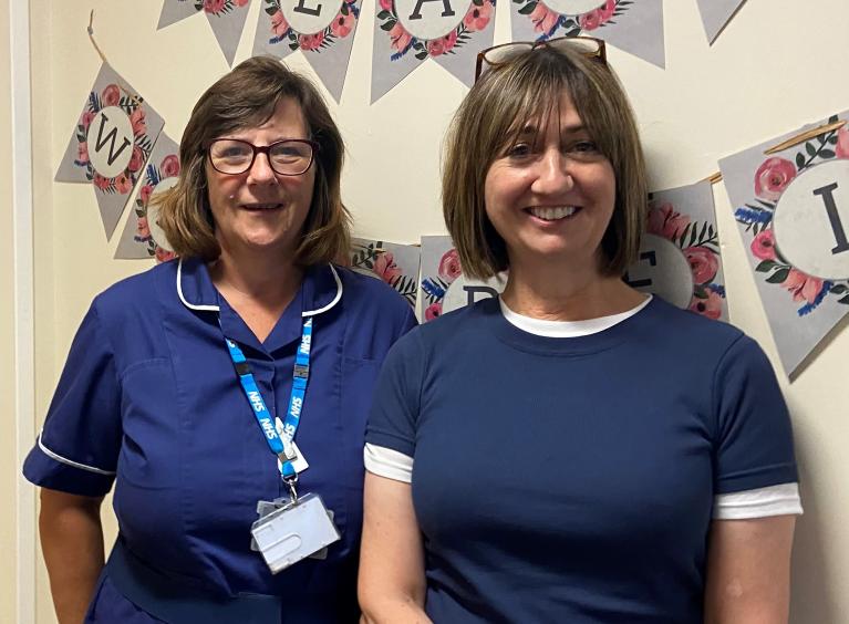 Two women from the Safeguarding team stood in front of a wall