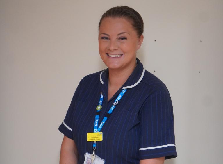 Erica is smiling and wearing a nurse uniform