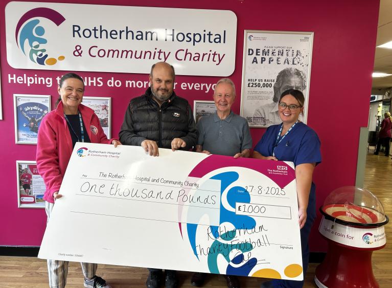 Four people holding a large charity cheque for £1,000