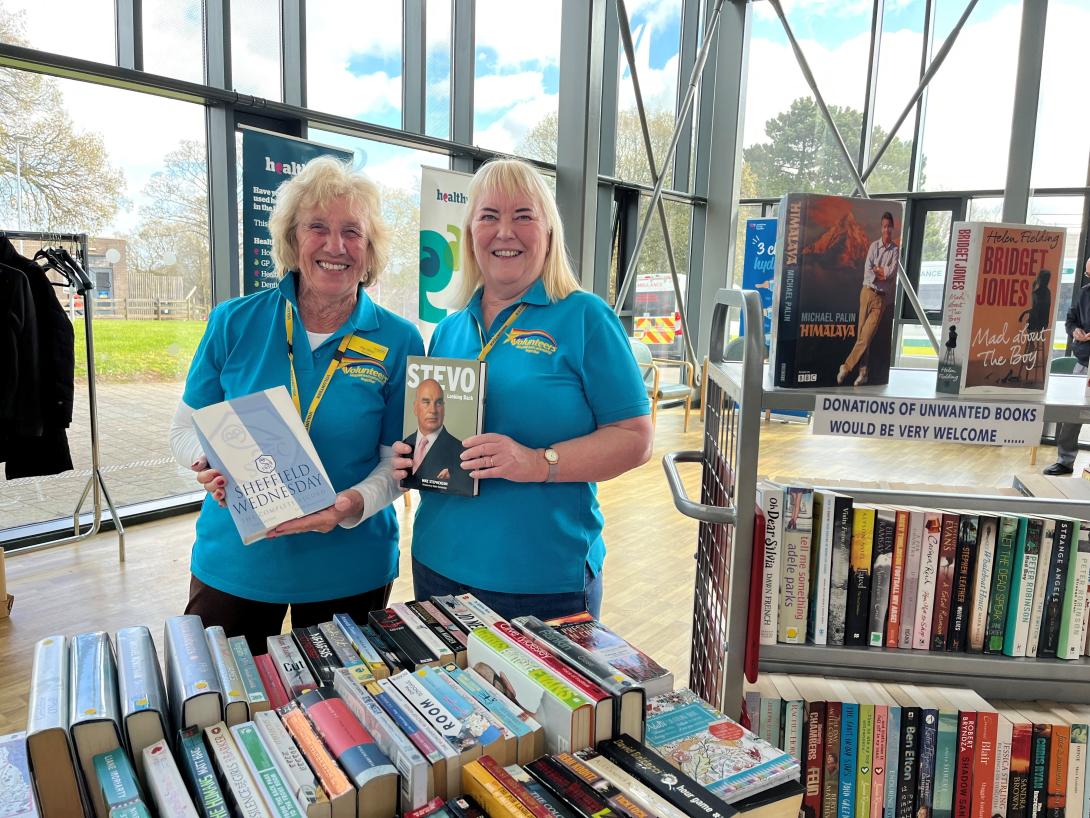 Two volunteers in blue t-shirts holding books