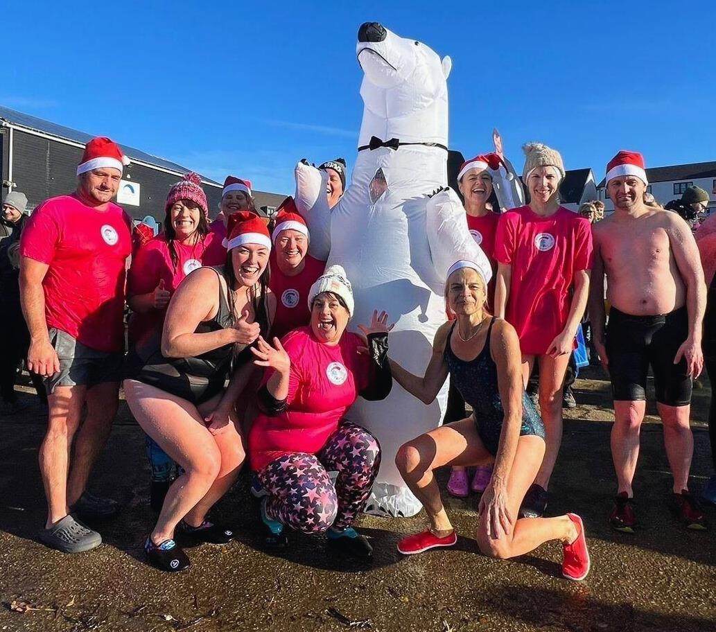 Polar plungers from November 2023 wearing pink tshirts with the charity logo, alongside someone in an inflatable polar bear costume
