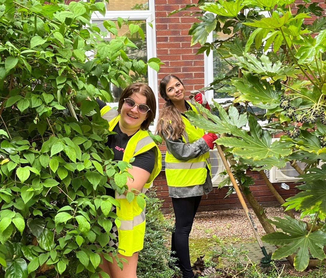 Two corporate volunteers in a green space at Rotherham Hospital.
