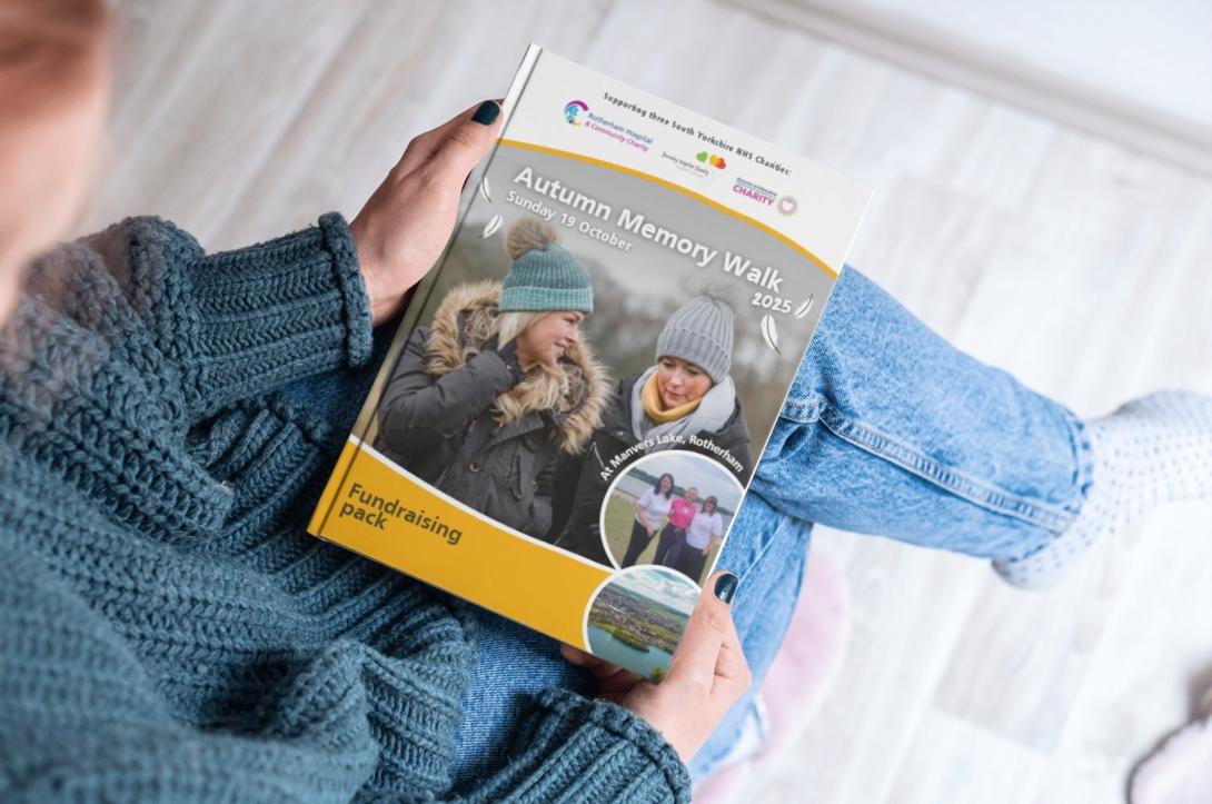 Someone holding the Autumn Memory Walk fundraising pack, looking at the front cover,