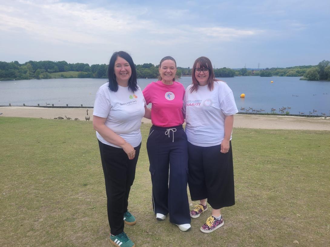 Three charity staff members dressed in charity T-shirts posing at Manvers Lake in Rotherham.