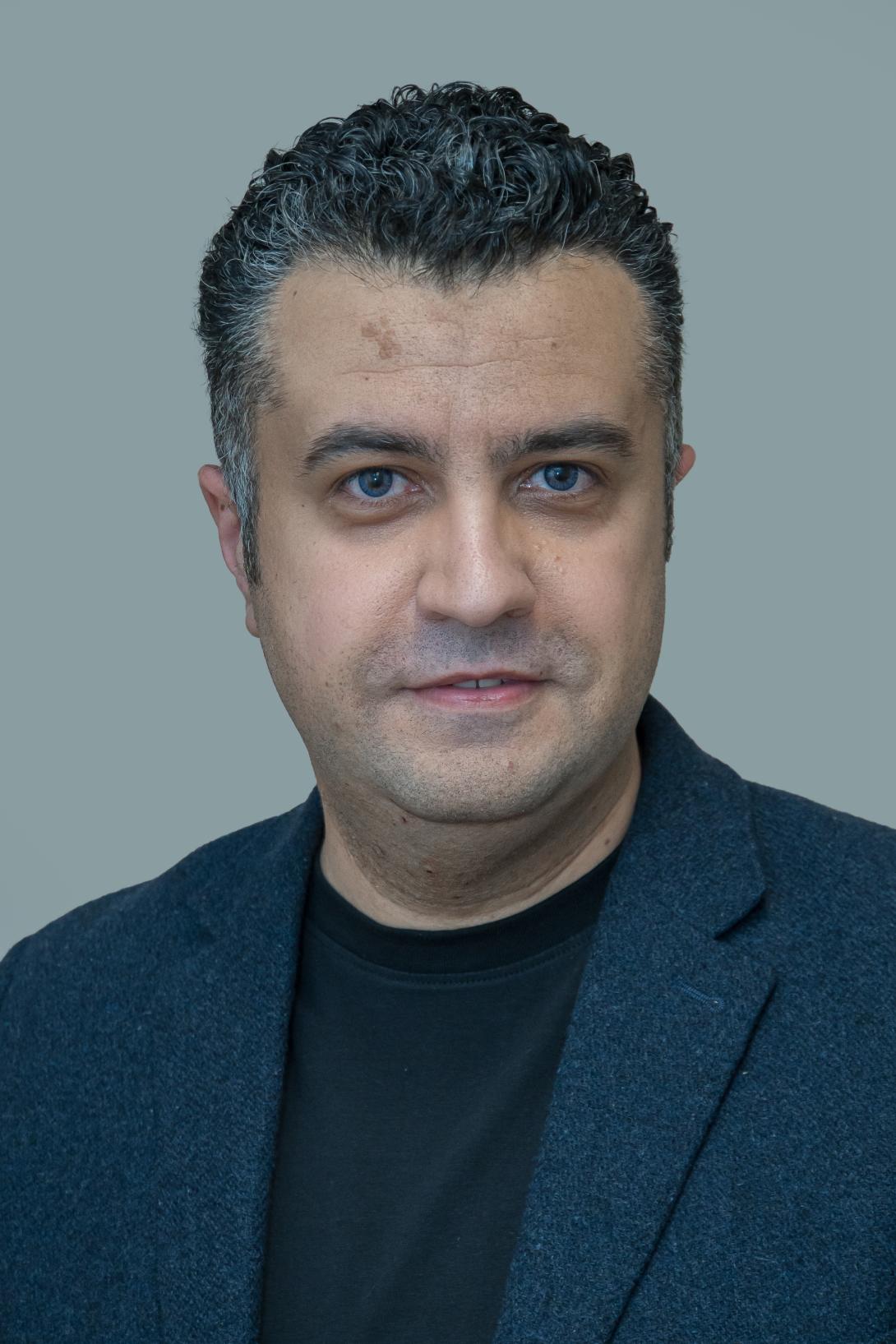 Amr is wearing a black top under a navy jacket