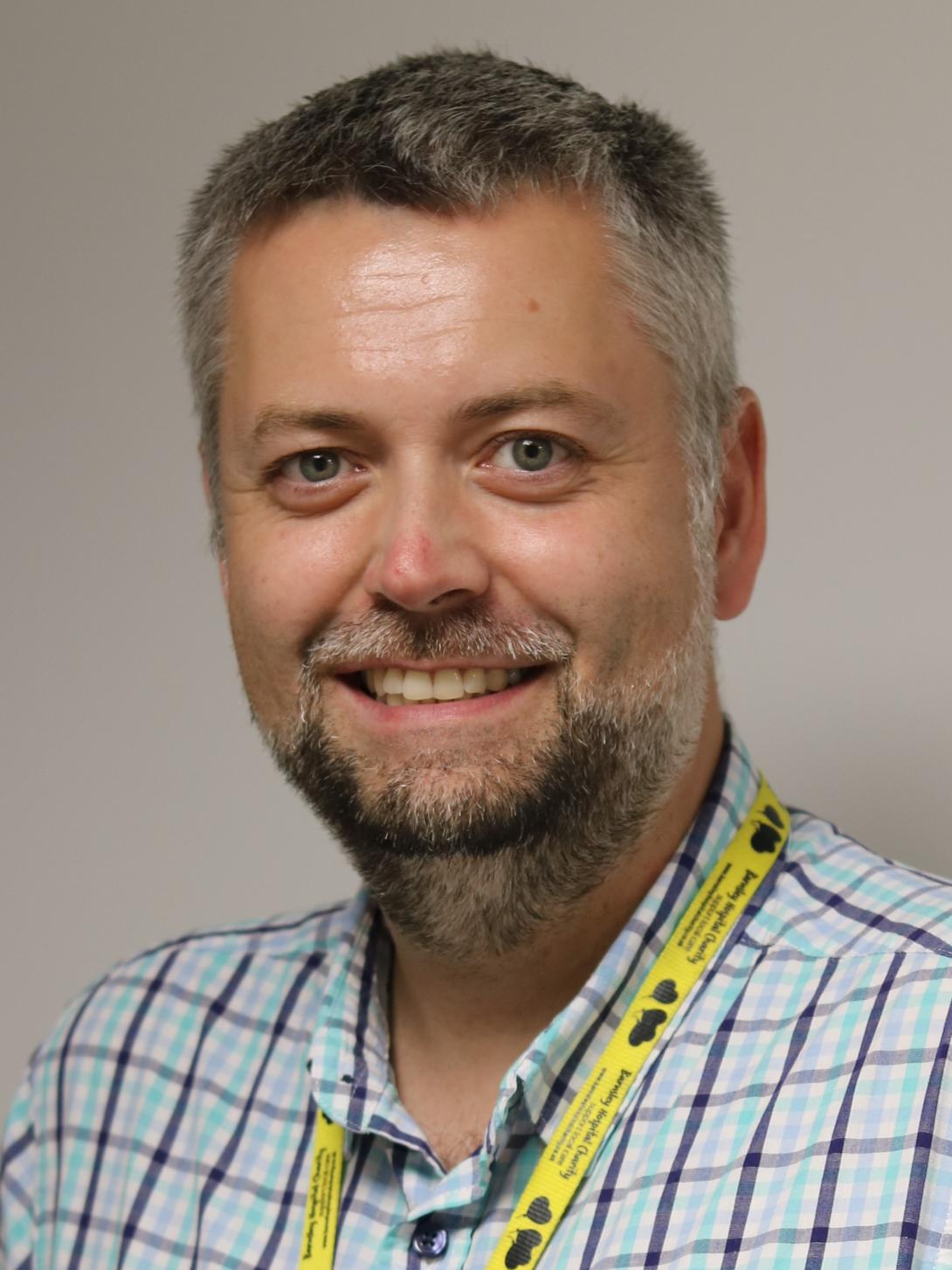 Chris is wearing a chequered shirt and a yellow lanyard